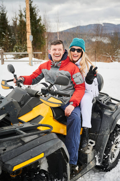 Portrét šťastného muže a ženy pózujících na čtyřkolce ATV. Koncepce aktivního volného času a zimních aktivit. - Fotografie, Obrázek