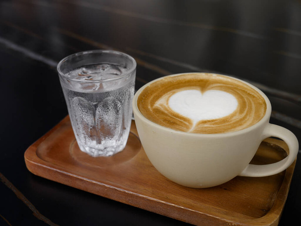 De koffie kunst met hart vorm in de beker op de donkere tafel en kopieer ruimte achtergrond - Foto, afbeelding