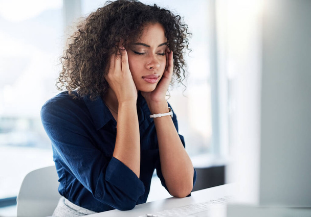 Los dolores de cabeza son una forma segura de detener la productividad. una atractiva joven empresaria que se ve estresada mientras trabaja en su escritorio en la oficina - Foto, imagen