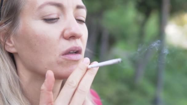 Close-up, een vrouw steekt een sigaret aan en neemt een trekje. - Video