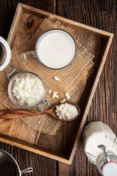 Kefir, gesundes probiotisches Getränk mit Milchkefir-Körnern auf Holzgrund - Foto, Bild