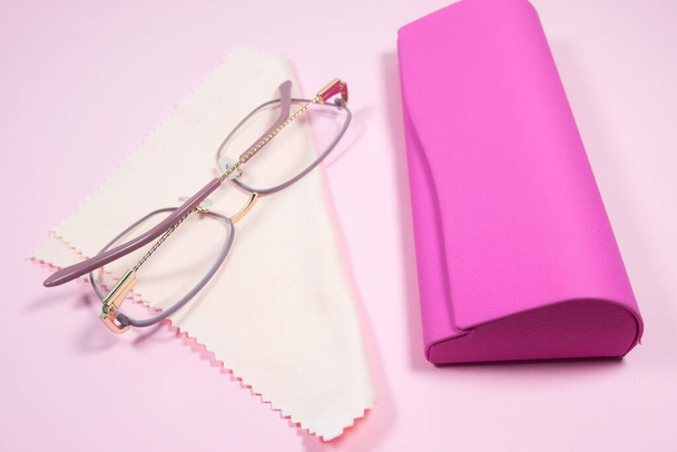 Occhiali da donna cornice rosa con occhiali pulizia panno e caso su uno sfondo rosa. - Foto, immagini