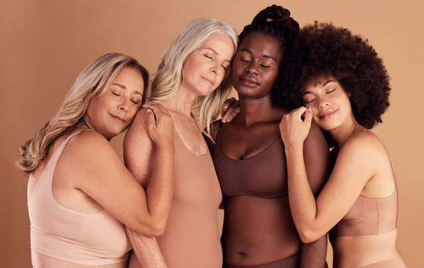 Support, diversity and women with hug for body positive marketing, solidarity and advertising underwear on a studio background. Collaboration, affection and model friends hugging for empowerment. - Photo, Image