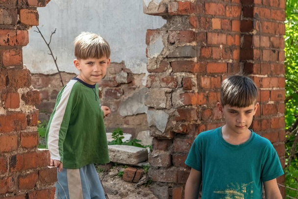 Two little brothers are orphans, living in an abandoned and abandoned house, children of war. Staged photo. - Photo, Image