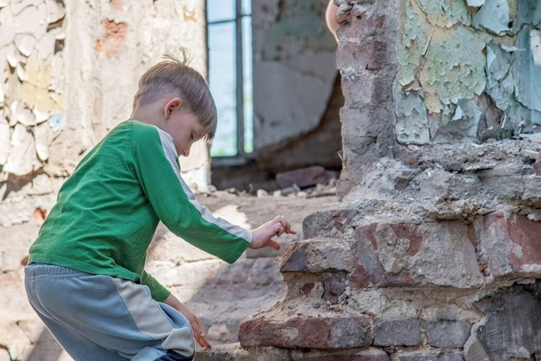 Children in an abandoned and destroyed building in the zone of military and military conflicts. The concept of social problems of homeless children. Staged photo. - Photo, Image