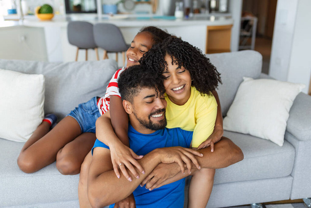 gelukkig familie moeder vader en kind dochter lachen en gedrag plezier thuis. Gelukkige Afro-Amerikaanse familie ontspannen - Foto, afbeelding
