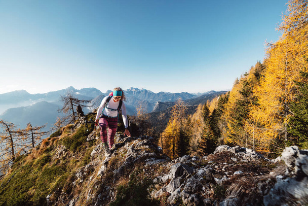 Widok na jesienną górę, Alpy Europejskie, z punktu widzenia, gdzie stoi biała kobieta turystka. Słońce świeci wysoko w górach. Lekka mgła w dolinach. Kobieta. - Zdjęcie, obraz
