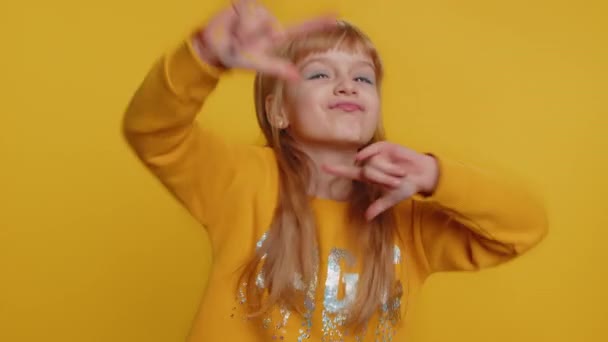 Overjoyed happy young child girl kid showing rock n roll gesture by hands, cool sign, shouting yeah with crazy expression, dancing, rejoicing in success. Little toddler children on yellow background - Footage, Video