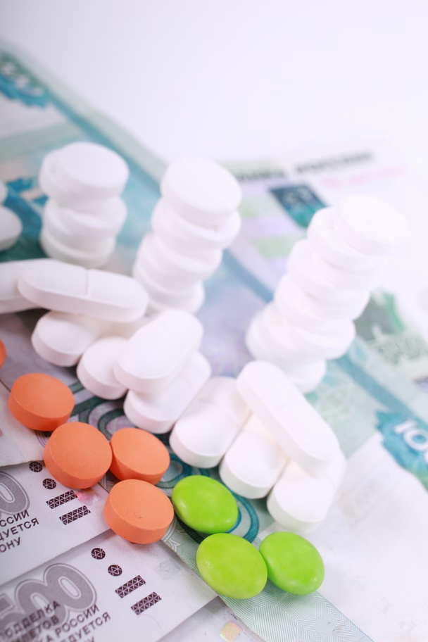 Pills of different colors on money background. - Photo, Image