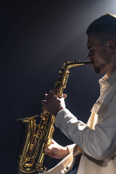 Músico masculino en el escenario toca el saxofón oscuro con humo, espacio para copiar. - Foto, imagen