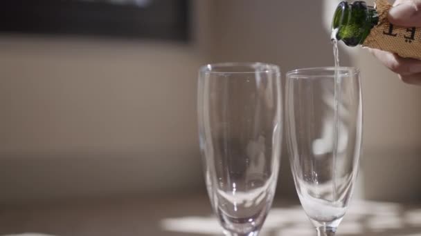 Close-up van het gieten van champagne in elegante wijnglazen. Actie. Transparante champagneglazen voor afspraakjes. Champagne per glas gieten op zonnige dag.  - Video