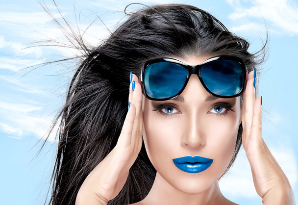 Hermosa modelo sosteniendo gafas de sol de moda en la frente
 - Foto, imagen