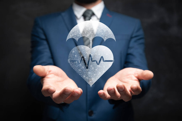 Сердце и зонтик. Концепция медицинского страхования. Человек держит в руке - Фото, изображение