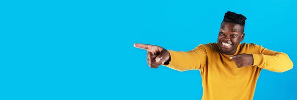 Перевір це. Веселий чорний хлопець, який вказує на копіювання простору двома руками, молодий афроамериканський чоловік вказує на вільне місце для реклами, стоїть ізольовано на синьому фоні, панорама
 - Фото, зображення