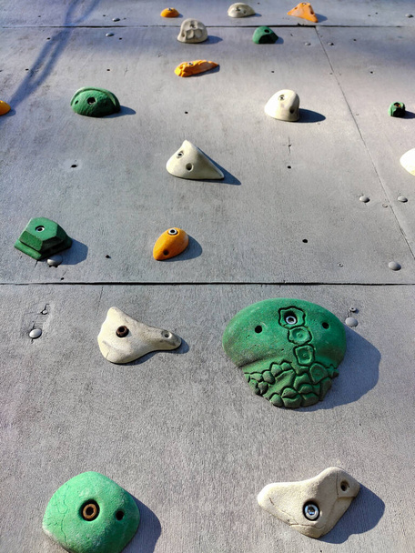 Primer plano de ganchos de diferentes formas y colores en una pared para el entrenamiento de escalada deportiva - Foto, imagen