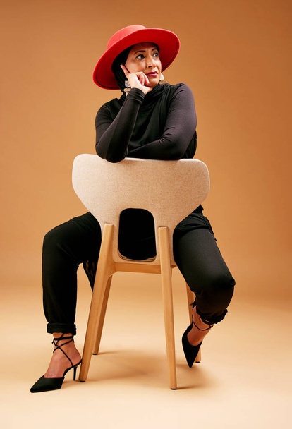 Schönheit, Mode und Seniorin auf Stuhl, stilvolles und elegantes Outfit. Islamische Frau, Dame und Kreative mit Designerklamotten, Luxus und braunem Studiohintergrund für Idee und trendige Vision - Foto, Bild