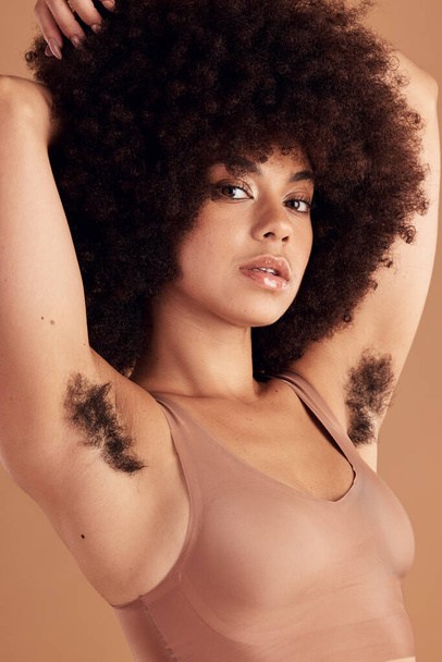 Armpit hair, body positivity en portret van een zwarte vrouw in de studio op een bruine achtergrond voor natuurlijke verzorging. Gezondheid, welzijn en empowerment met een aantrekkelijk jong Afrikaans vrouwtje dat haar oksel laat zien. - Foto, afbeelding