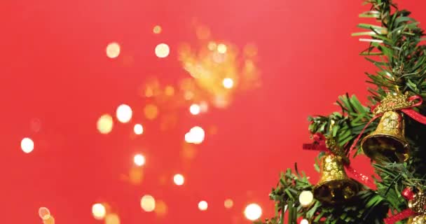 Karácsonyfa díszített arany harangok bokeh fények piros háttér. Boldog Karácsonyt és Boldog Új Évet Ünneplés 2023. - Felvétel, videó