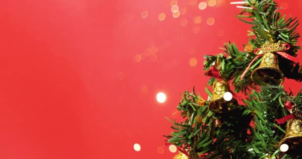Árbol de Navidad decorado con campanas doradas con luces bokeh sobre fondo rojo. Feliz Navidad y Feliz Año Nuevo. - Metraje, vídeo
