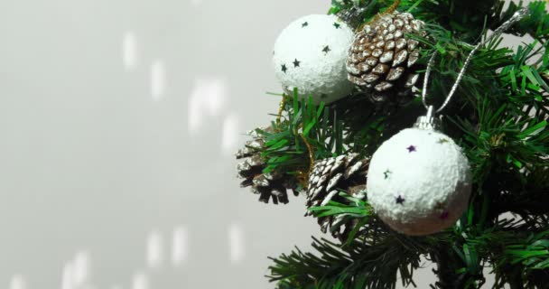 Christmas tree branches with falling snowflakes. Hang pinecone from Christmas tree branches with white snowballs. Merry Christmas and Happy New Year 2023. - Footage, Video