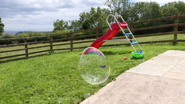 Bolla di sapone gigante con una bacchetta della bolla in un giardino - Foto, immagini