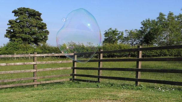Obrovská mýdlová bublina s bublinkovou hůlkou v zahradě - Fotografie, Obrázek