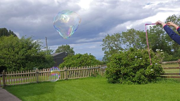 Óriási szappanbuborék buborékpálcával a kertben - Fotó, kép