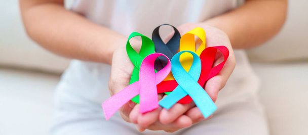 Wereldkankerdag, 4 februari. Hand met blauwe, rode, groene, roze, zwarte en gele linten voor het ondersteunen van mensen leven en ziekte. Gezondheidszorg en Autisme bewustmakingsdag concept - Foto, afbeelding