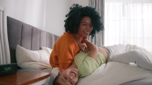 Любляча афроамериканська мама обіймає спокійного гарненького хлопця, який лежить у ліжку. Посміхаючись турботливою змішаною расовою матір'ю і милою маленькою дитиною, яка обіймається в спальні. Мама з дитиною ніжні хвилини веселяться повільніше - Кадри, відео