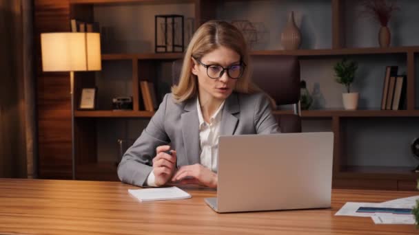 Uzaktan eğitim, İngilizce dersi. Gözlüklü genç bir kadın dizüstü bilgisayarda konferans görüşmesi yapıyor. Çalışan, evden çalışan ve webcam sohbeti öğrenen bir grup insanla. - Video, Çekim