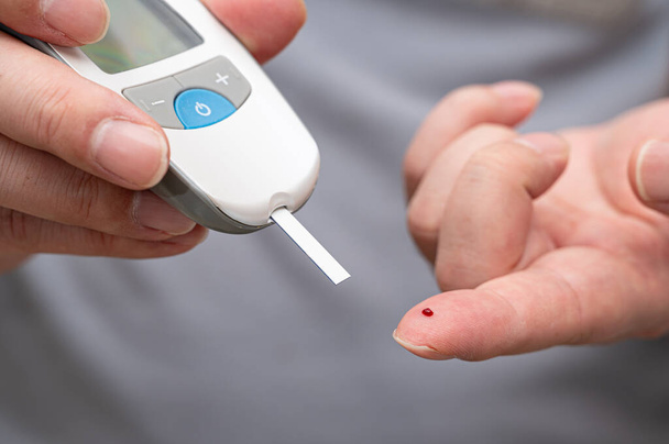 Man measures his blood sugar. Glucometer, blood sample test, diabetes concept. - Photo, Image