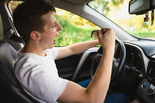 Nováček křičící v autě za volantem a mávající pěstí ohrožuje dalšího motoristu. Špatné a agresivní chování na silniční koncepci. - Fotografie, Obrázek