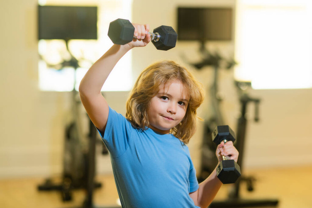 Child workout kid in gym. Kid sport. Child exercising with dumbbells. Sporty child with dumbbell - Photo, Image
