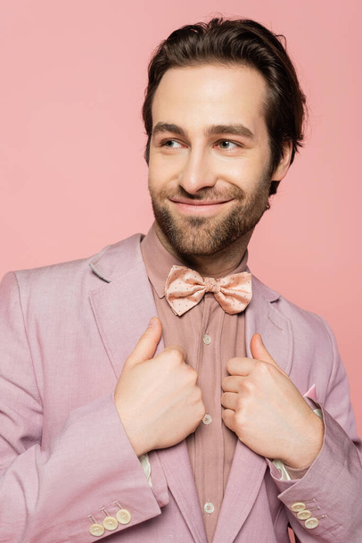 Portrait of stylish host of event adjusting jacket isolated on pink  - Photo, Image