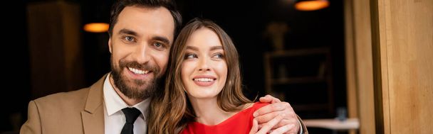 portrait of cheerful and bearded man looking at camera while hugging girlfriend, banner  - Foto, Imagem