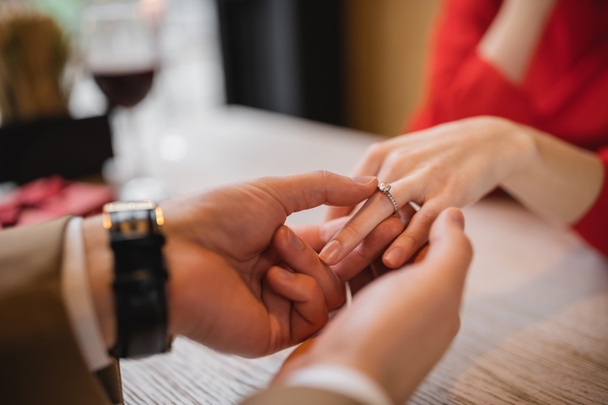 vista ritagliata dell'uomo che fa la proposta e indossa l'anello di fidanzamento al dito della fidanzata il giorno di San Valentino  - Foto, immagini