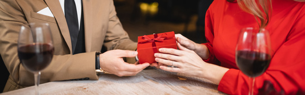 частичный вид мужчины, держащего завернутый подарок рядом с женщиной на день святого Валентина, баннер   - Фото, изображение
