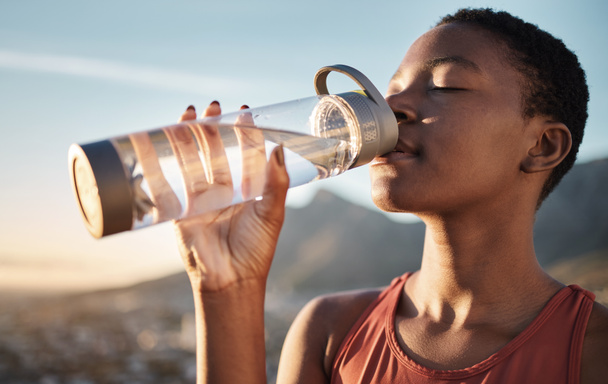 Spor, siyah kadın ve idmandan sonra su şişesi içmek, egzersiz ve açık hava kardiyo çalışması. Susamış genç sporcu, spor susuzluğu ve sağlıklı yaşam için beslenme, sağlıklı vücut ve enerji. - Fotoğraf, Görsel