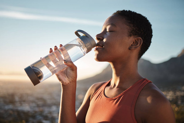 Water, hydration and black woman running in nature, fitness rest and health for exercise in Turkey. Energy, break and training African runner drinking water for body detox during an outdoor workout. - Photo, Image