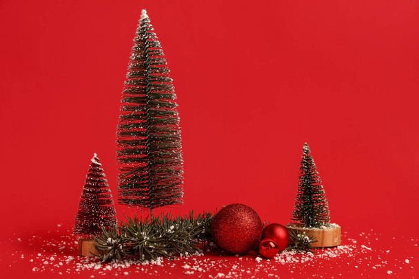 Koostumus koriste joulukuuset, pallot, havupuiden oksa ja lunta punaisella pohjalla - Valokuva, kuva