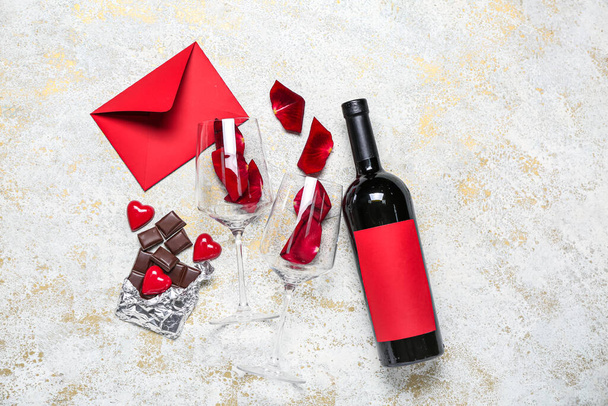 Μπουκάλι κρασί, ποτήρια, ροδοπέταλα, σοκολάτα και φάκελος σε φόντο grunge. Γιορτή του Αγίου Βαλεντίνου - Φωτογραφία, εικόνα
