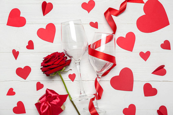 Bicchieri con nastro, cuori e rosa su fondo bianco in legno. Festa di San Valentino - Foto, immagini