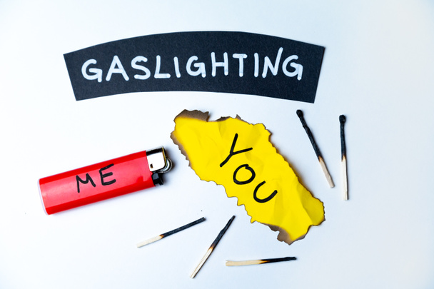 Word Gaslighting, on a black surface, next to a lighter with the word Me, and burnt yellow card with the writing You. Psychological meaning. - Photo, Image