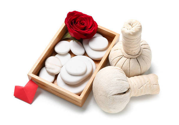 Gyönyörű spa kompozíció Valentin-napra rózsával, gyógynövény táskák és kövek fehér alapon - Fotó, kép