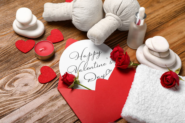 Gyönyörű fürdő összetétele Valentin-nap boríték, rózsa virágok, kövek, törölköző, gyertyák és gyógynövény táskák fa háttér - Fotó, kép