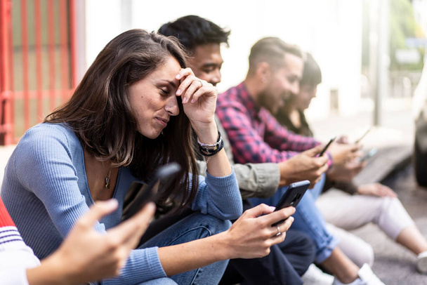Umfangreiche Freundesgruppe mit Smartphone im Hinterhof der Universität - Junge Leute süchtig nach Handy - Technologie trauriges Lebenskonzept mit immer vernetzten Studenten - Lebendiger Filter - Foto, Bild