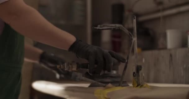Handheld-Aufnahme einer anonymen Technikerin, die Schleifmaschine und Scheibe nimmt und dann tagsüber in einer sonnendurchfluteten Garage arbeitet - Filmmaterial, Video