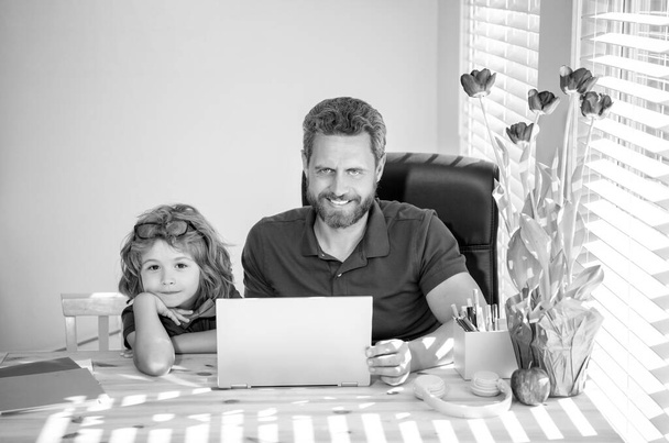 bearded dad or school private tutor teaching boy son with modern laptop, education. - 写真・画像