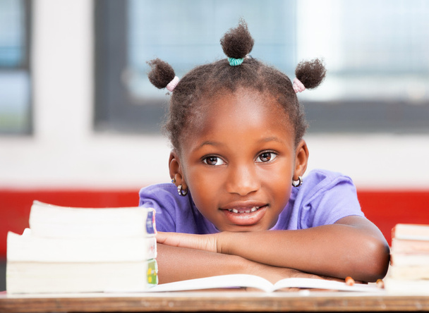 afroamerikanische Studentin liegt auf dem Schreibtisch zwischen Büchern - Foto, Bild