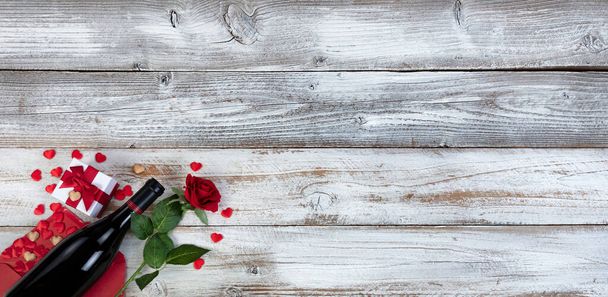 Κόκκινο κρασί με φάκελο καρδιές, δώρο κουτί παρόν και κόκκινο τριαντάφυλλο σε λευκό ρουστίκ φόντο ξύλο για μια ευτυχισμένη ημέρα του Αγίου Βαλεντίνου έννοια  - Φωτογραφία, εικόνα